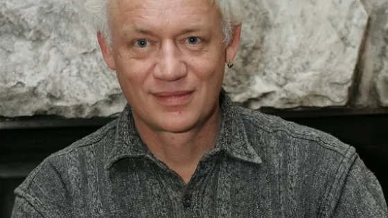 Photo of man with blue eyes and white hair wearing patterned shirt