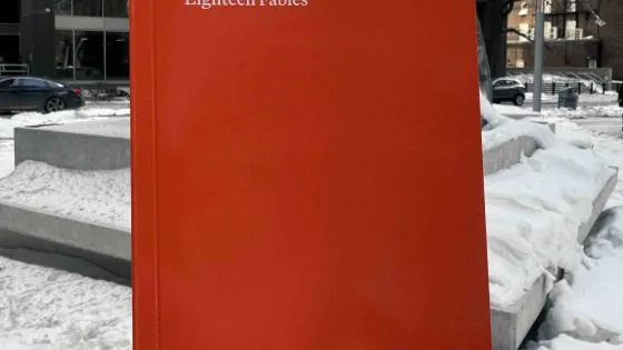 Holding bright orange book to cover the public artwork