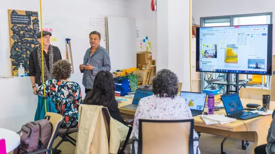 People in a research lab attending a presentation led by two faculty members.