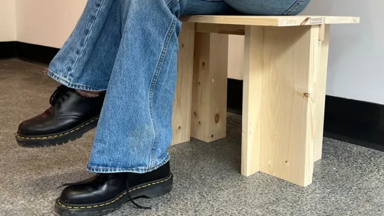 Person sitting on a wooden stool