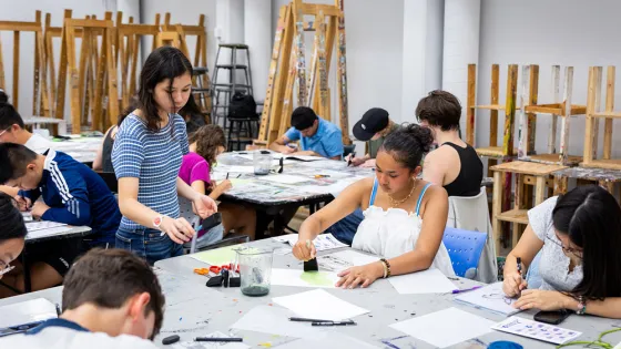 Young students working at communal tables in a painting studio