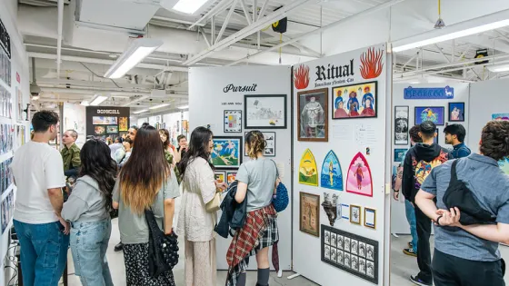 Group of people walking around GradEx 110, seeing illustrations on plinths