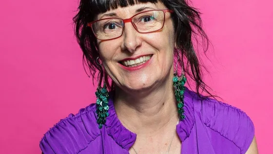 A woman with short black hair and wearing eye glasses with purple shirt