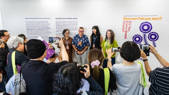 Four people standing at the back with people taking photos of them