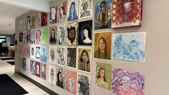 Colourful portraits displayed on a wall. 