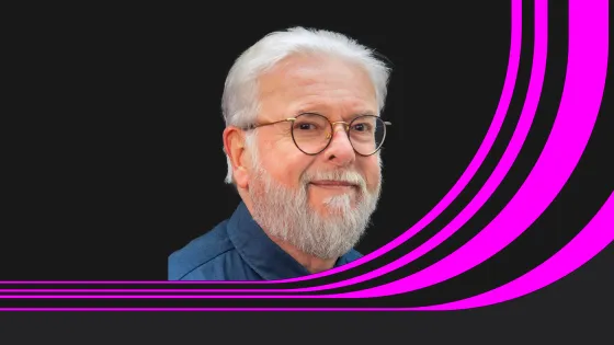 A protrait of professor Bill Leeming in blue shirt and black baackground.