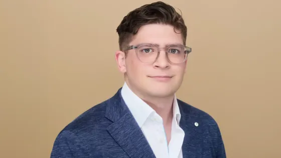 Photo of man with glasses wearing white shirt and blue blazer