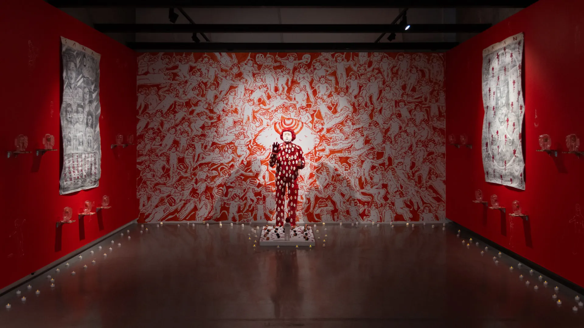 Installation view of Doktor Karayom: No One’s At Home (Walang Tao Sa Bahay). Red and white sculpture, in front of red and white wall mural.