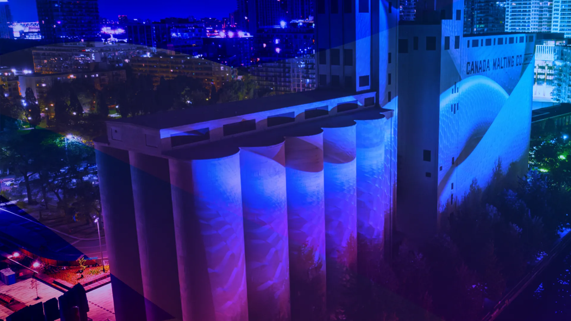 Photo of Canada Malting Siloes, a heritage building located at Toronto's Waterfront, overlayed with a blue, purple and pink gradient.