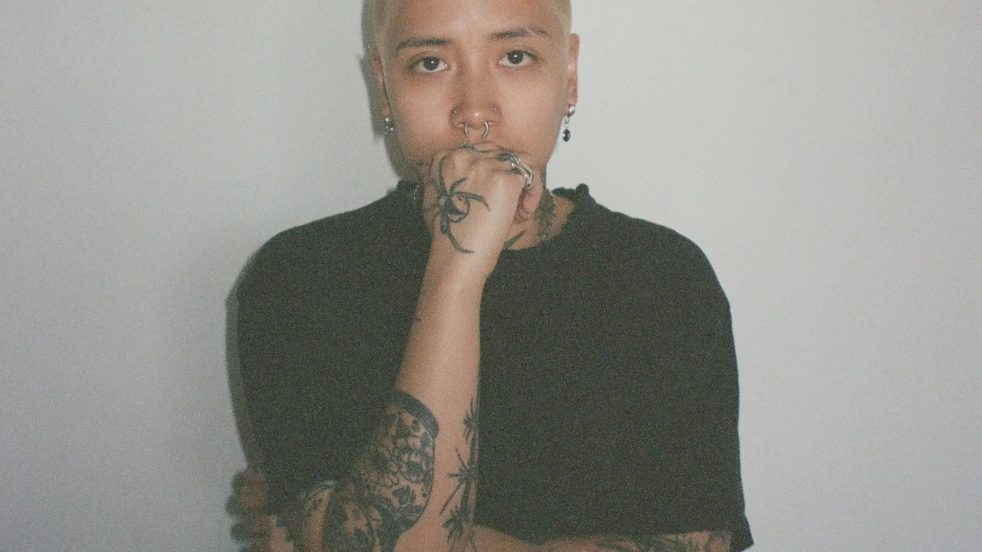 A woman wearing a black t-shirt with short blonde hair. 
