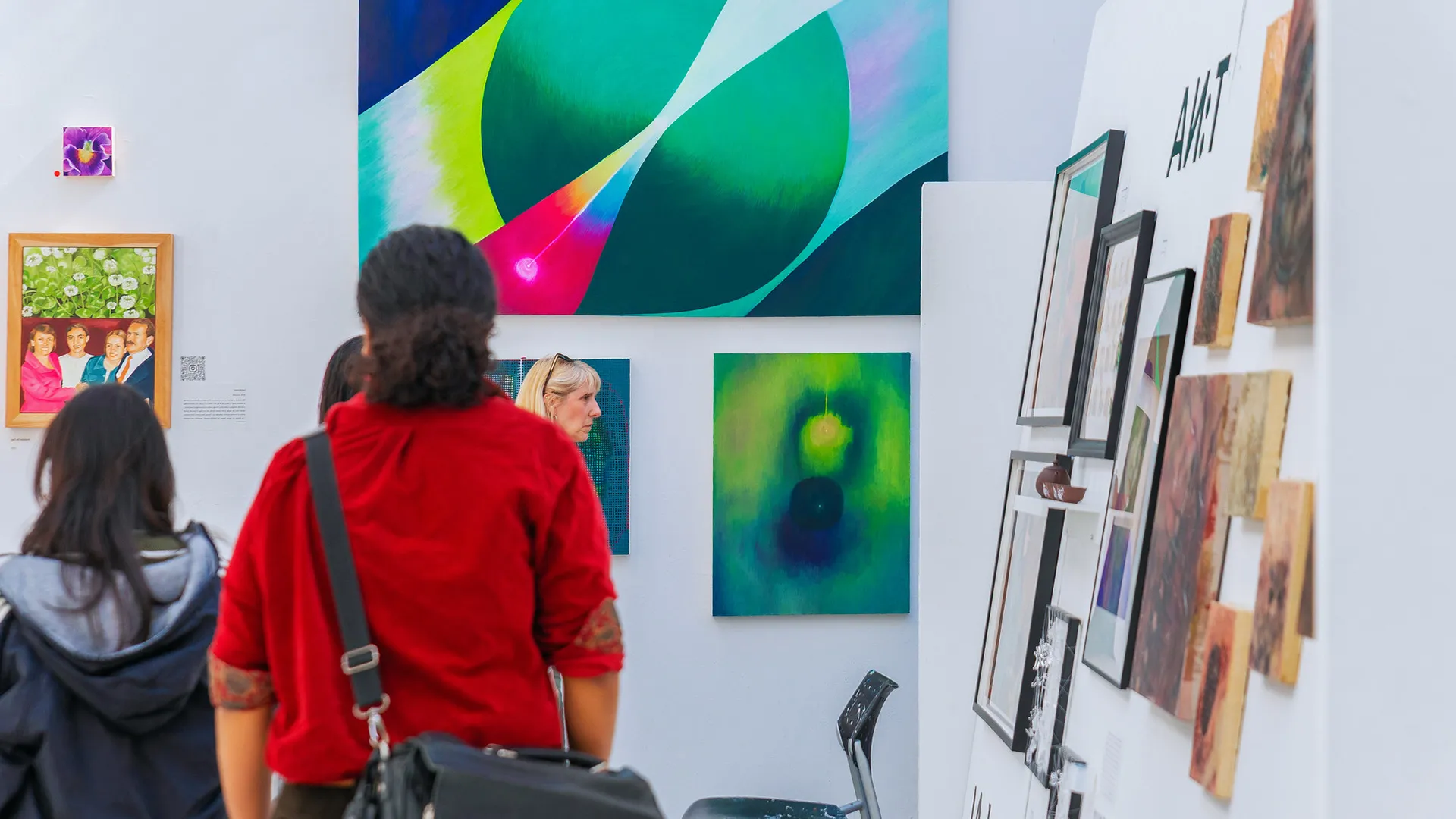 People looking at painting hung on white walls at GradEx