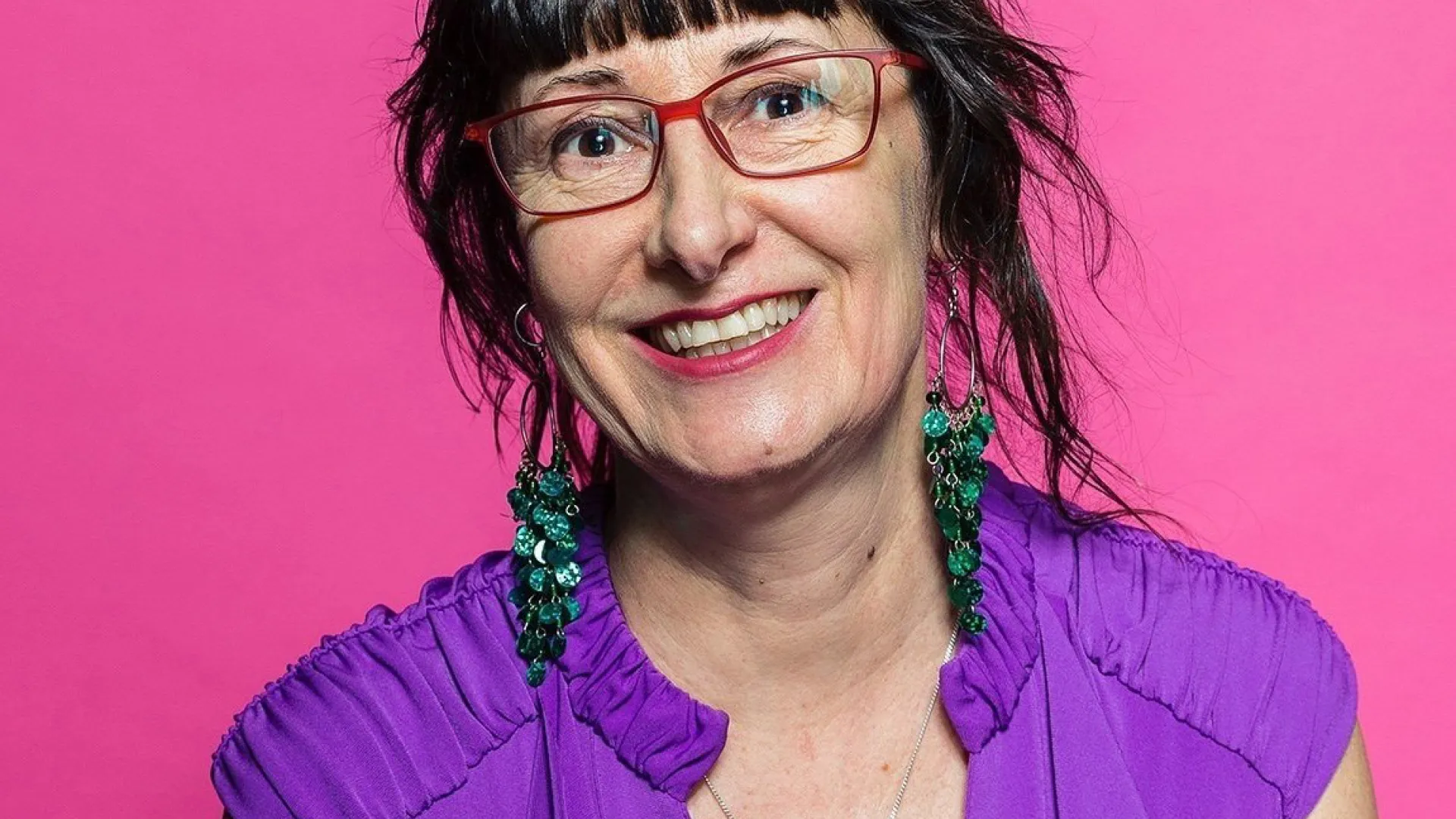 A woman with short black hair and wearing eye glasses with purple shirt