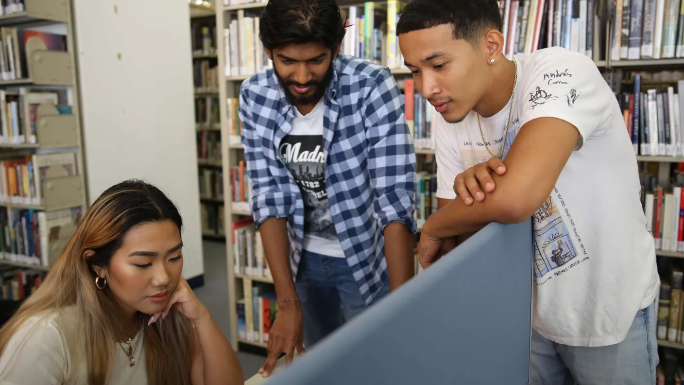 Three students at a library computer