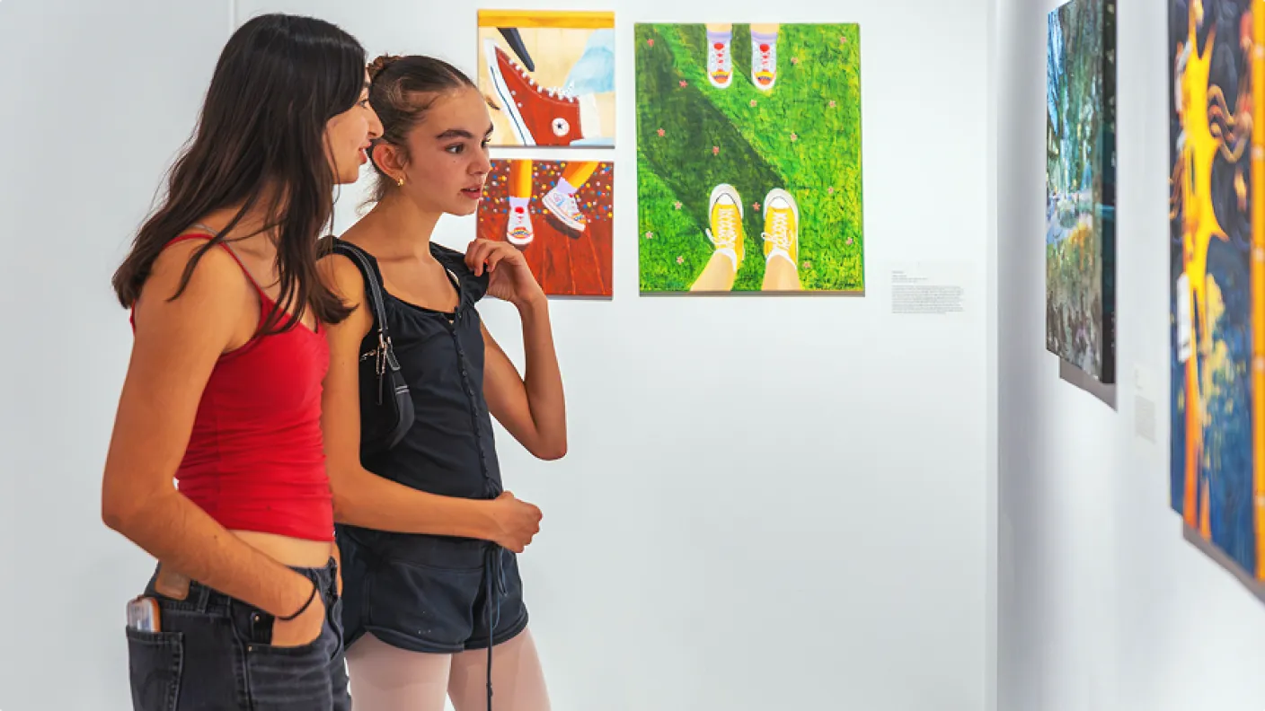 Two young people looking at art hung on white gallery walls