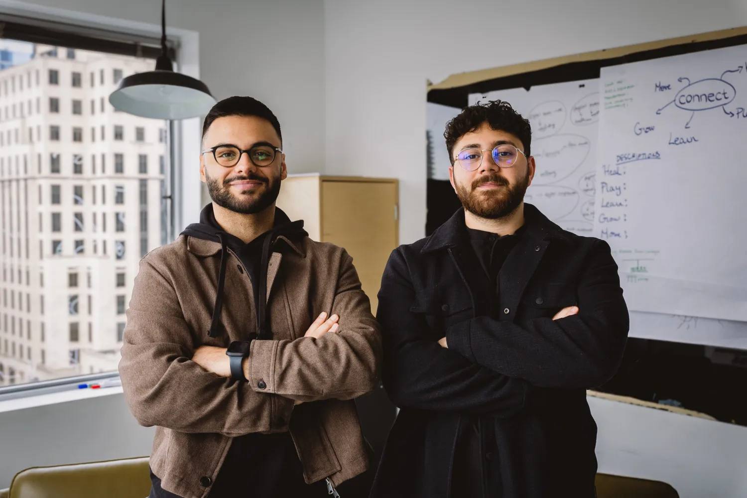 Award-winners Arian Shariaty (left) and Eli Saghbini (right) standing together in a meeting room. 