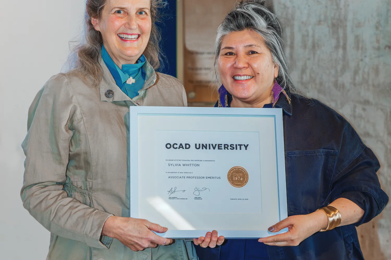 Ana Serrano and Sylvia Whitton stand holding a framed certificate.