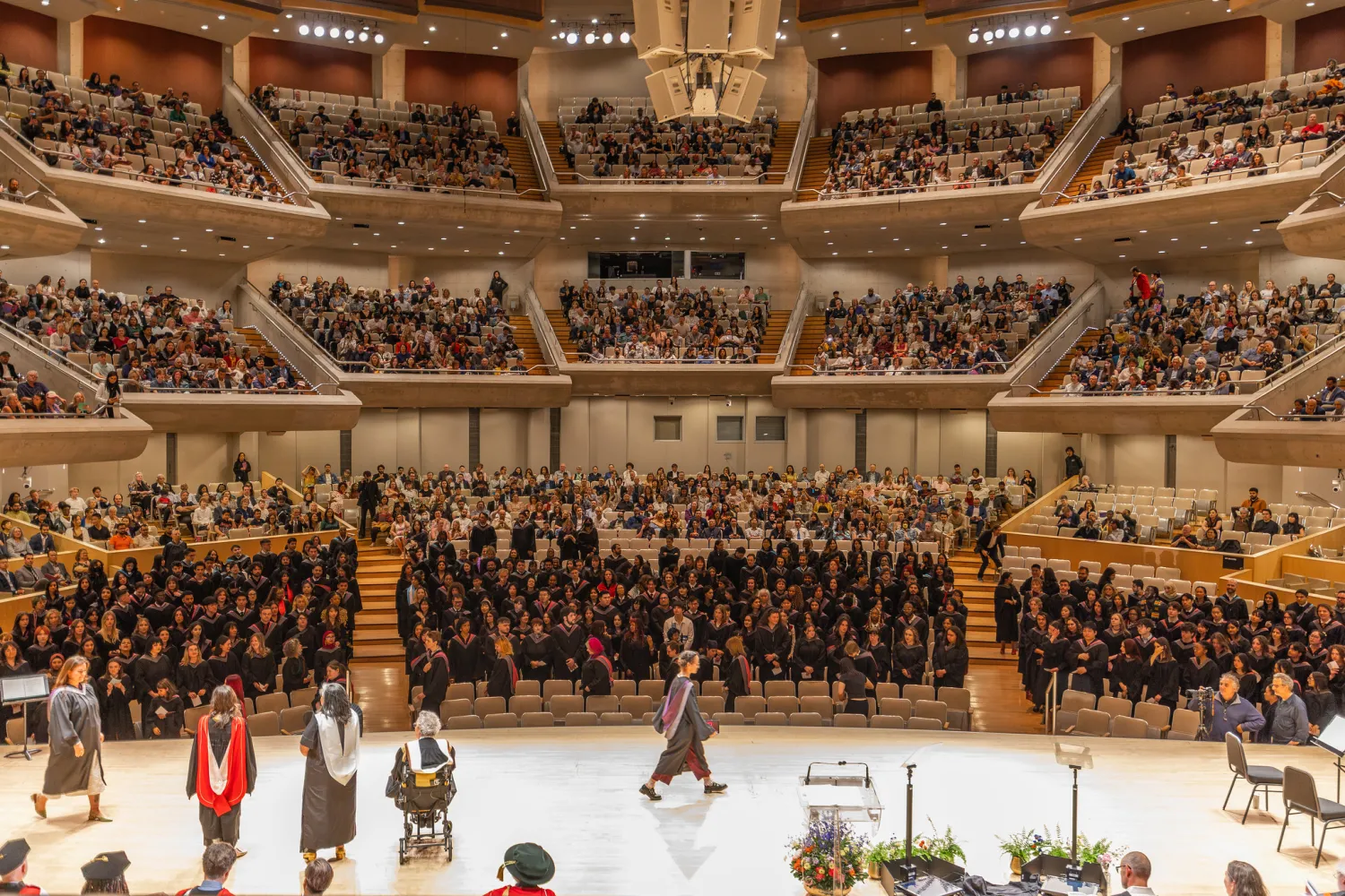 Convocation stage looking out onto crowd. Student crossing across the stage. 