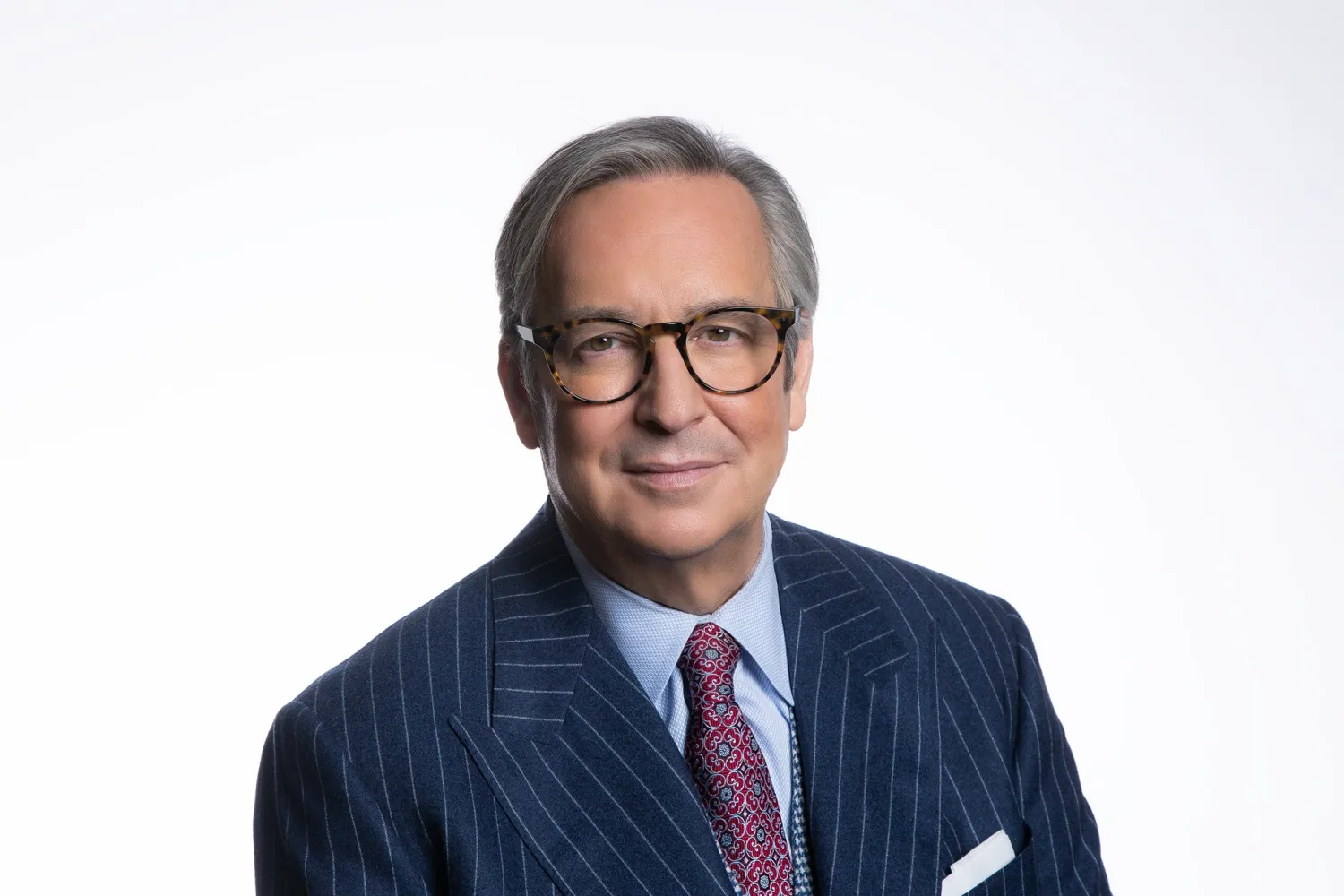 Colour photo of Chancellor Jaime Watt wearing a pin-striped navy suit and red patterned tie. 