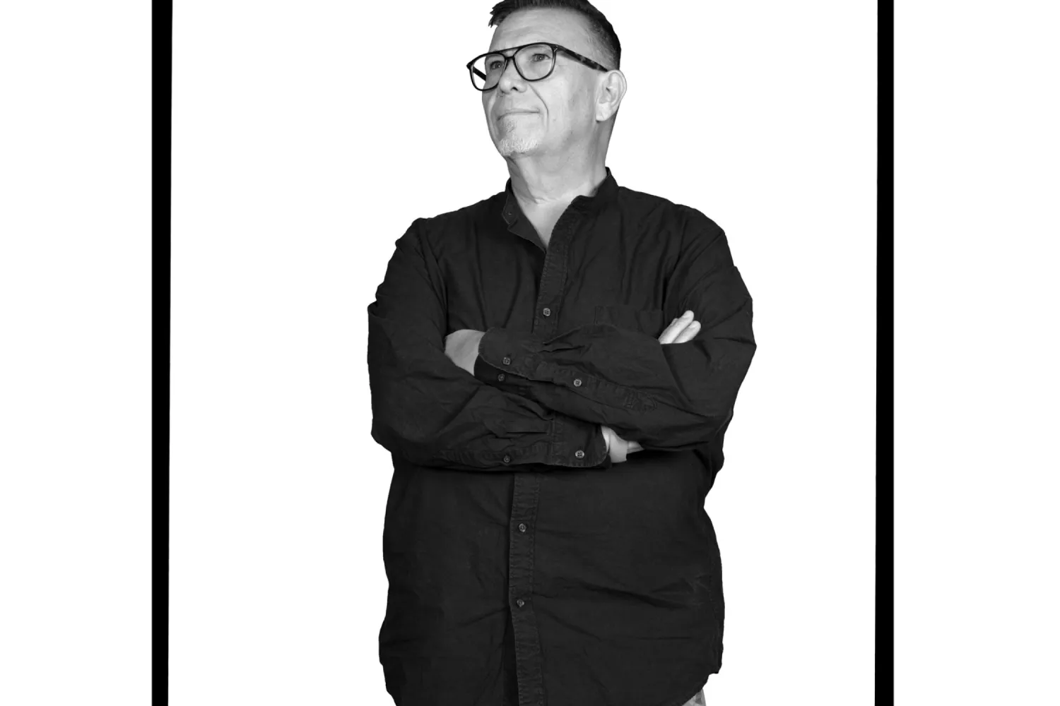 A man standing with arms crossed wearing eye glasses