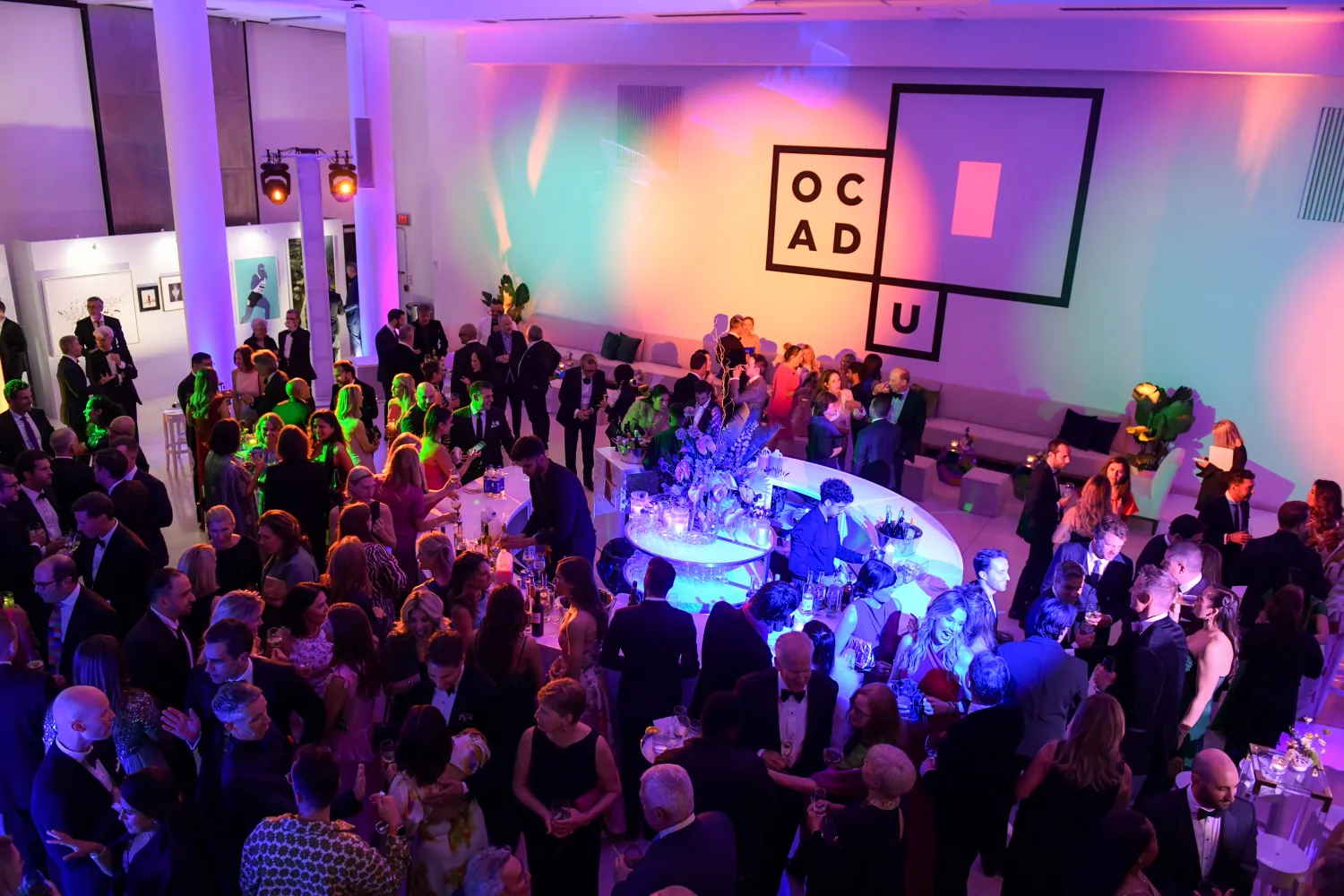 Guests mingle at the OCAD U Gala reception under colourful lighting.