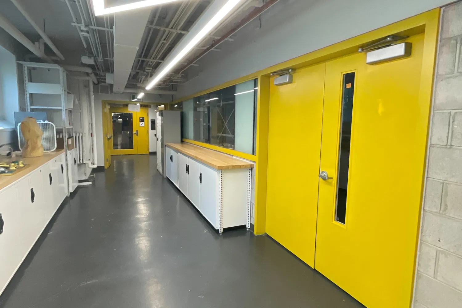 A view of a hallway at OCAD University. A set of yellow double doors is to the right of the hallway. 