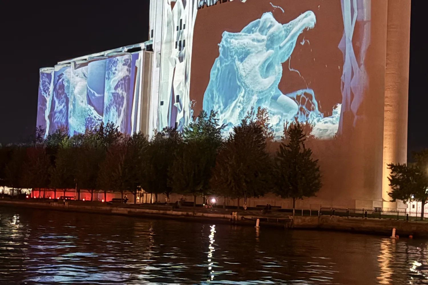 A photo of the Canada Malting Silos with a large-scale projection mapping that looks like water cascading down the building.