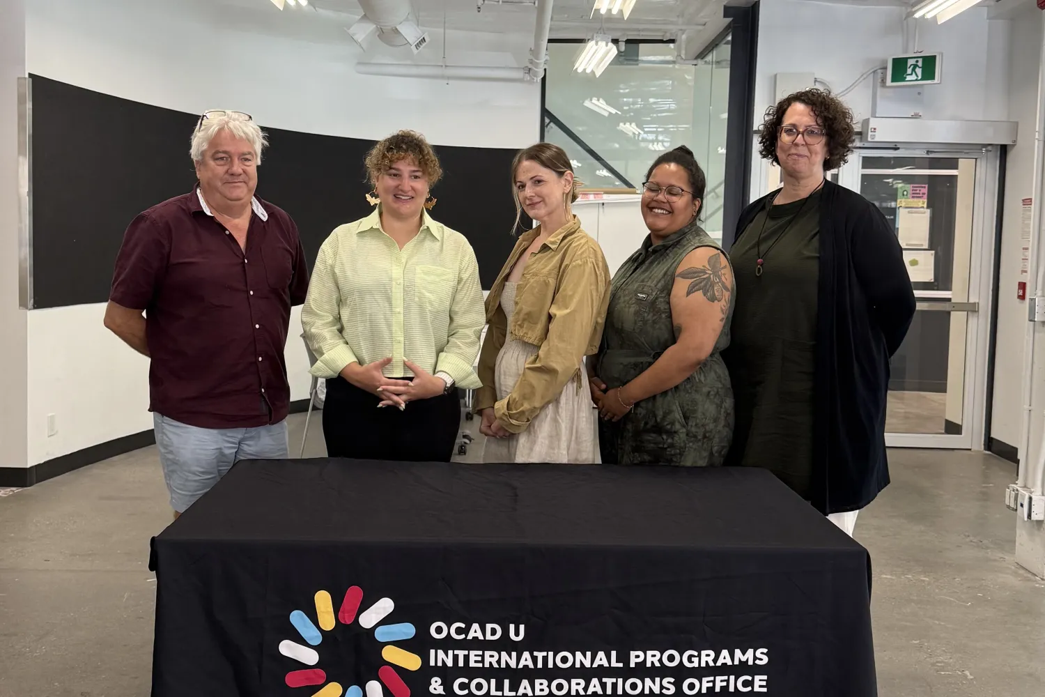 Image (left to right): Dr. David Griffin, Jennie Suddick, Meichen Waxer, Danielle Nadine Pierre and Deanne Fisher standing behind a table with a black tablecloth. The logo on the tablecloth says, "OCAD U International Programs & Collaborations Office."