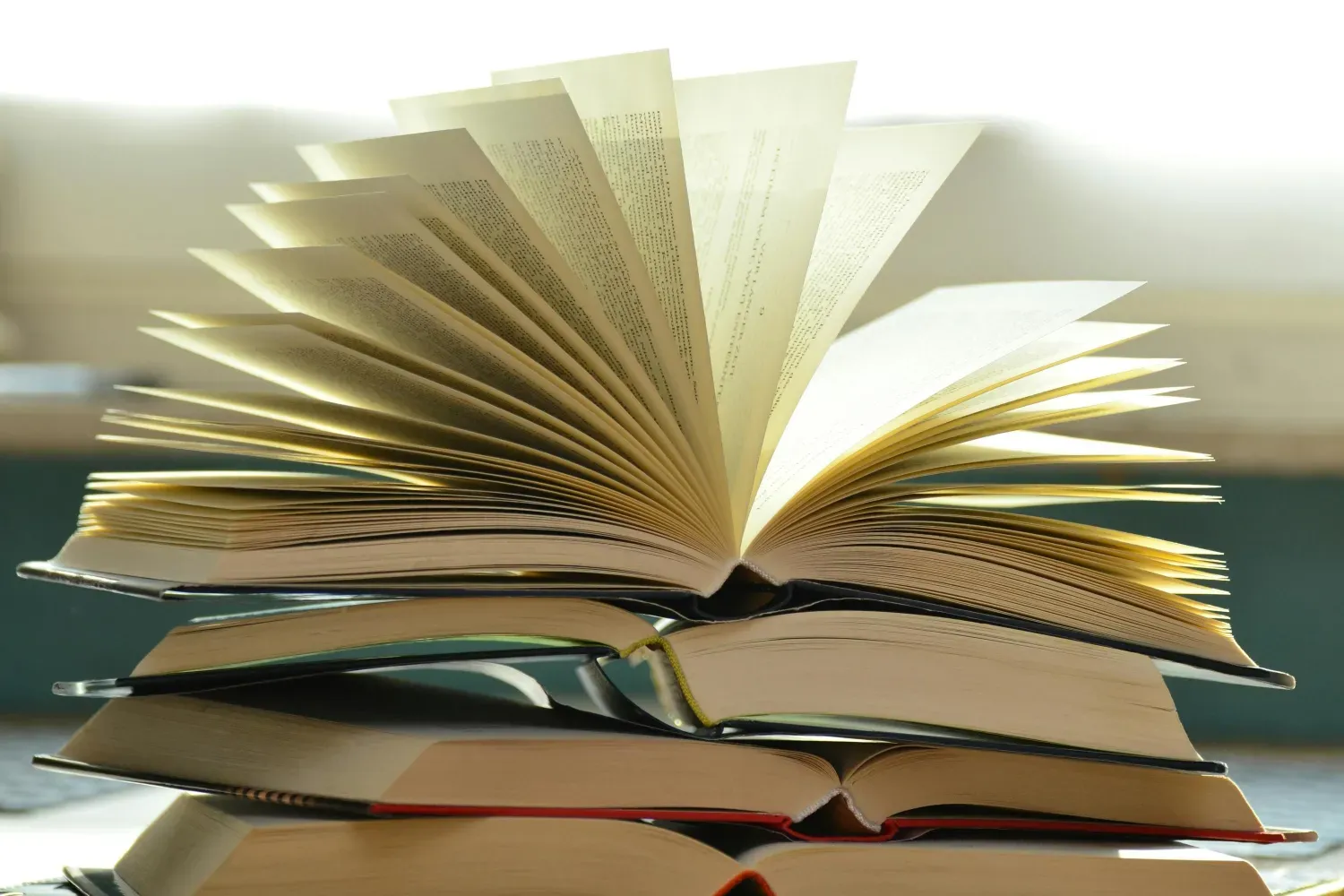 A pile of paper books with one book open pages