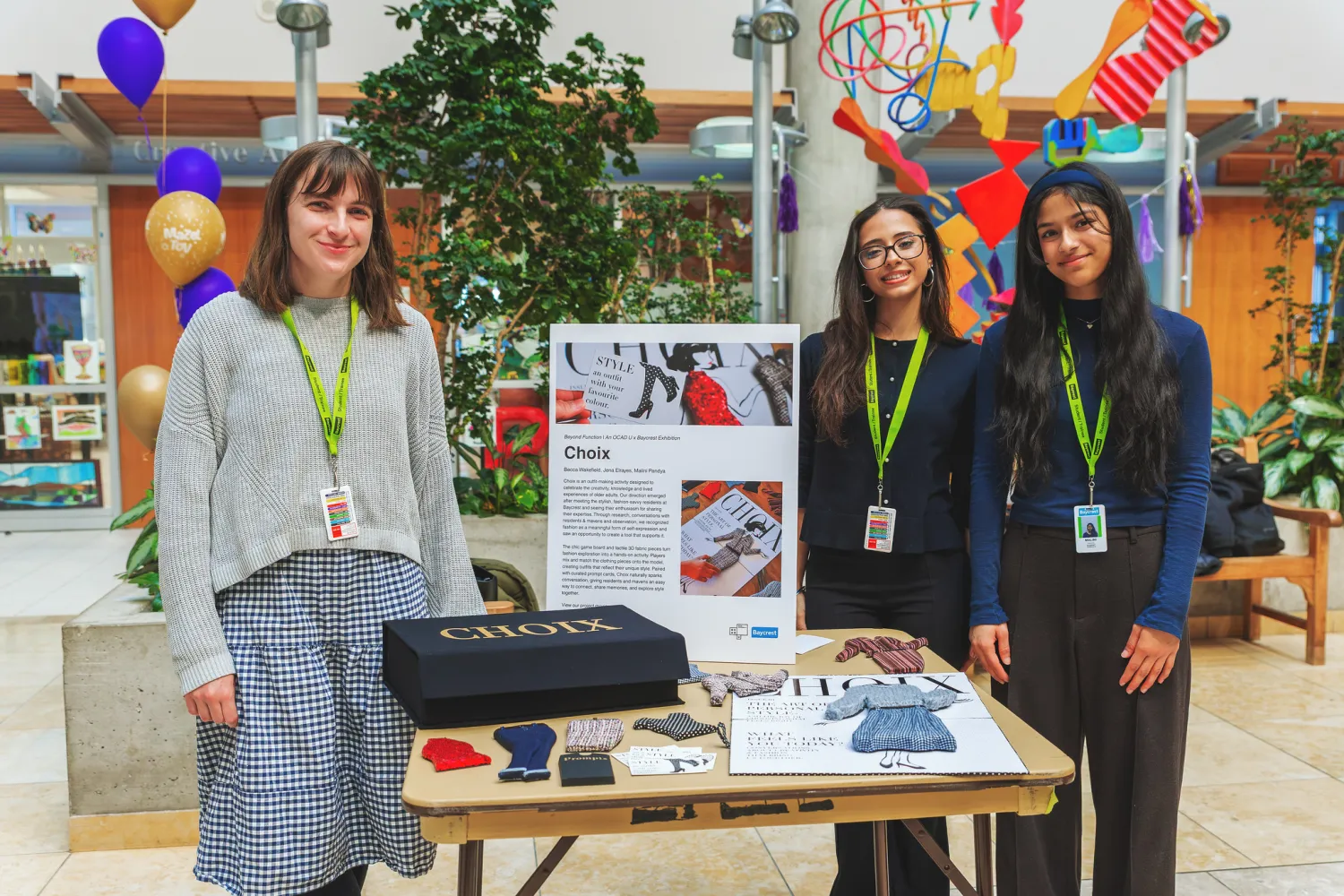Students standing next to display table of their product design. 