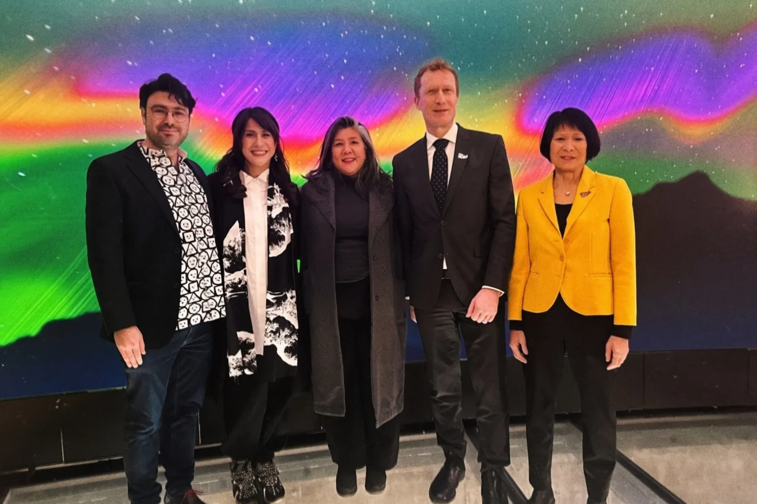 Five people standing in front of a colourful background