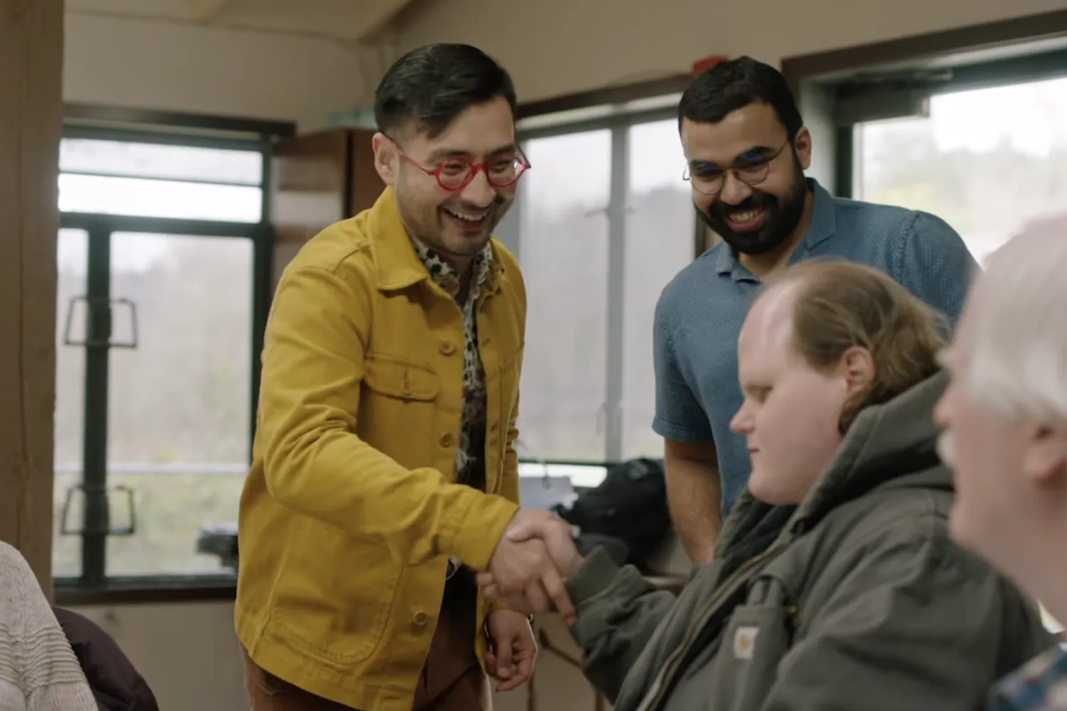 Four men, two are standing up and two are sitting. On the left (standing) is Patrick Burton; on the right (standing) is Aaditya Vaze.