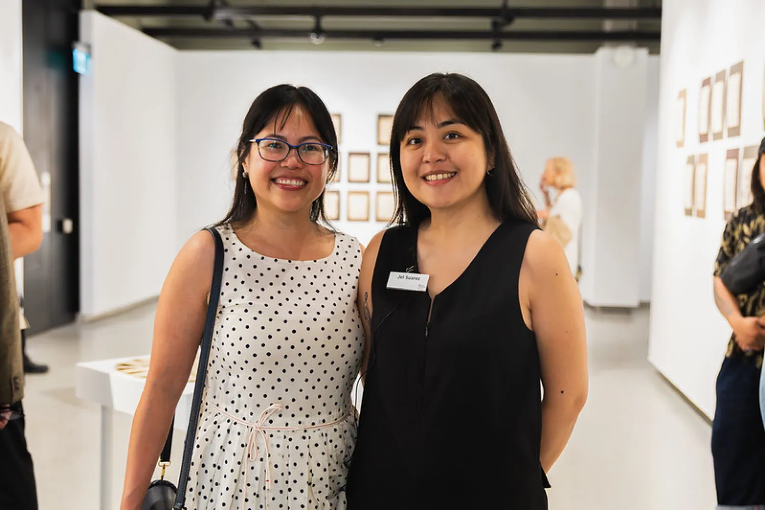 Two women side by side in an art gallery.