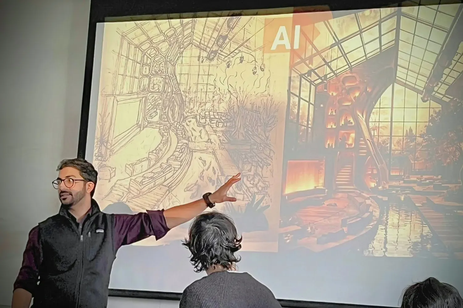 Photo of man at left with glasses pointing to a screen with two graphics