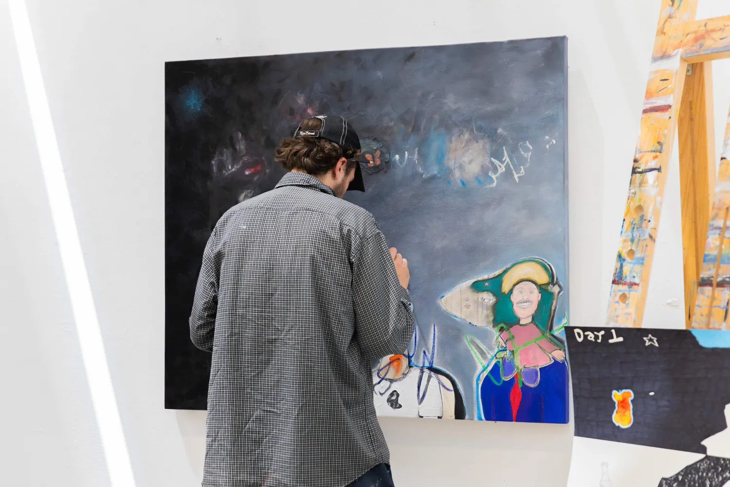 An artist doing final touches to a large abstract painting hanging on the wall