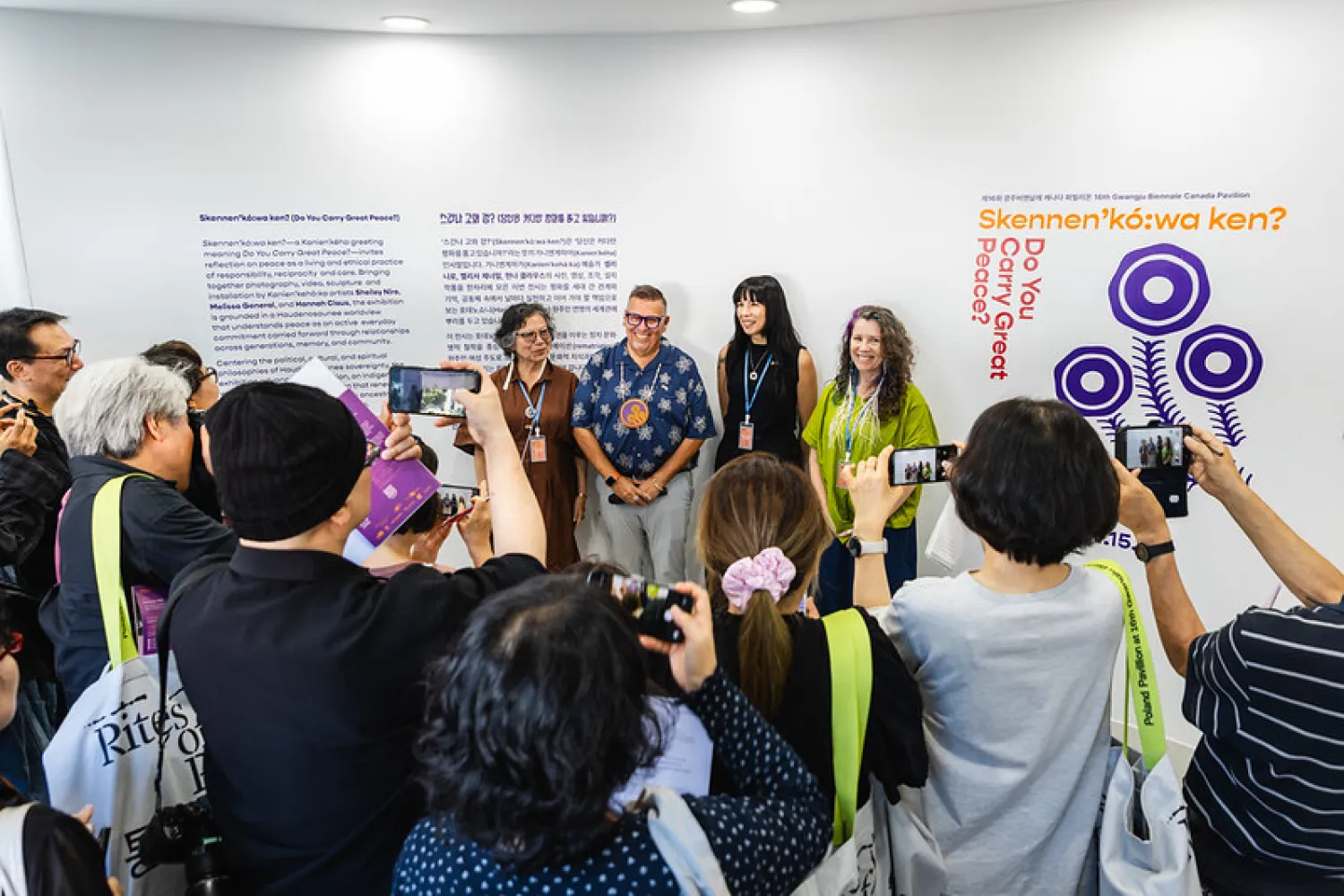 Four people standing at the back with people taking photos of them