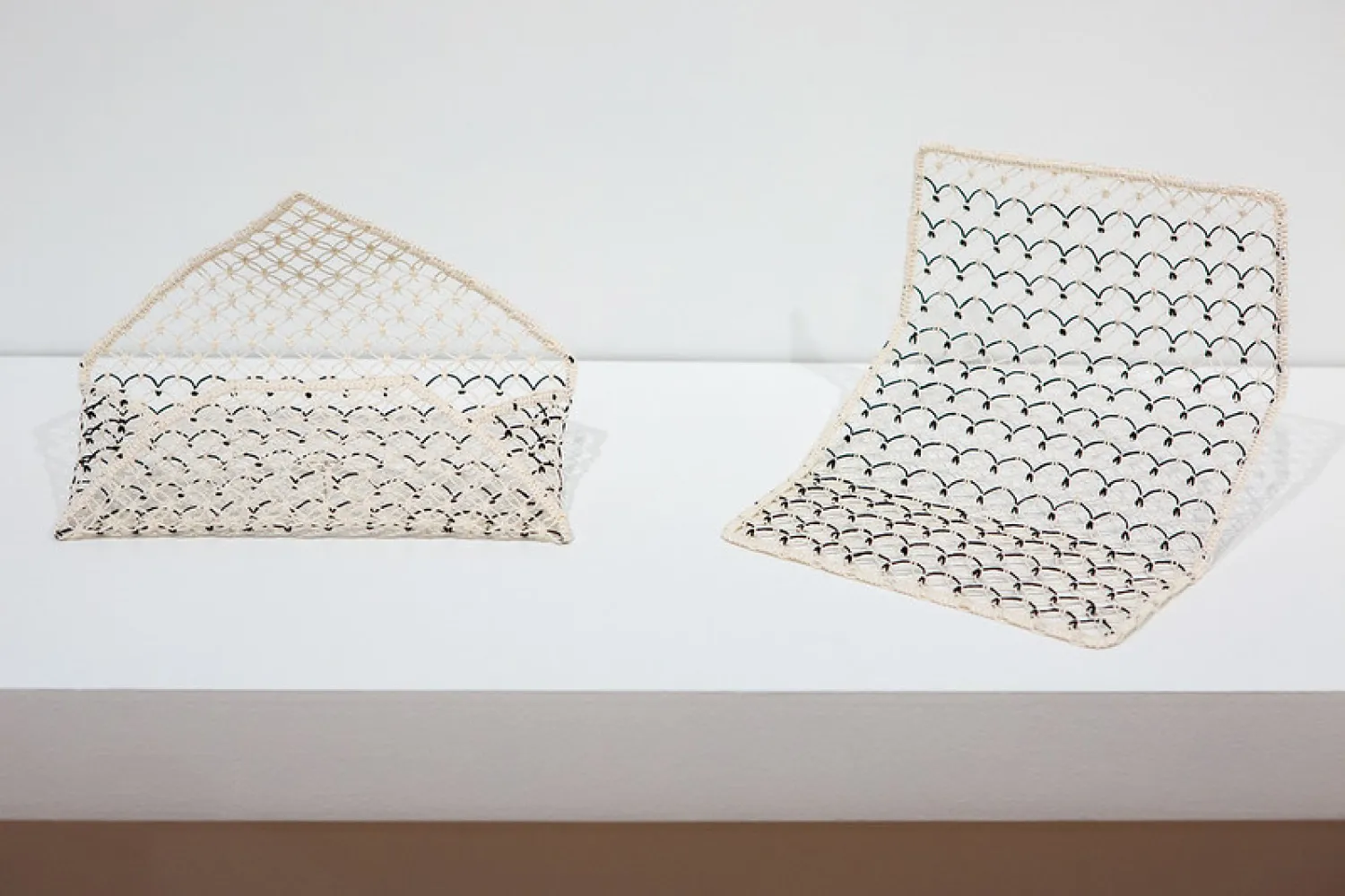 Image of two knotted paper sculptures, left looks like wallet, right looks like open wallet