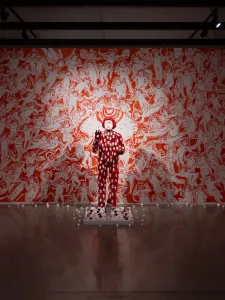 Installation view of Doktor Karayom: No One’s At Home (Walang Tao Sa Bahay). Red and white sculpture, in front of red and white wall mural.