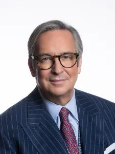 Colour photo of Chancellor Jaime Watt wearing a pin-striped navy suit and red patterned tie. 