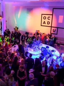 Guests mingle at the OCAD U Gala reception under colourful lighting.