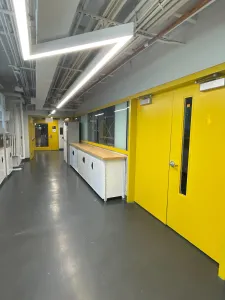 A view of a hallway at OCAD University. A set of yellow double doors is to the right of the hallway. 