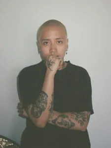 A woman wearing a black t-shirt with short blonde hair.