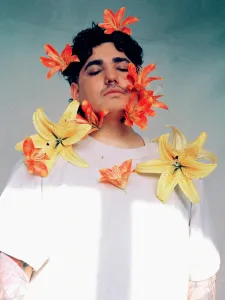 A man with black short hair wearing a white t-shirt with yellow and orange lilies on them