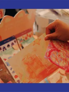 An individual holding a postcard in there hand at a tabeling event.