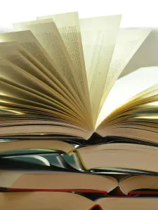 A pile of paper books with one book open pages