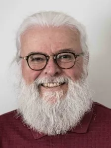 Photo of man with white hair and white beard wearing glasses