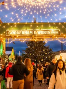 Distillery District during the holiday season. Festive lights hand overtop of a large crowd.