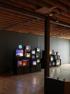 A number of TVs stacked on top of each other in an exhibition space.