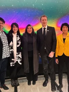 Five people standing in front of a colourful background