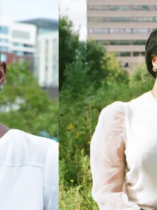 Two women: on the left a woman with short hair, wearing sunglasses and white shirt. One the left a woman with long dreadlocks and cream colored sweater.