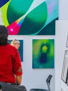 People looking at painting hung on white walls at GradEx